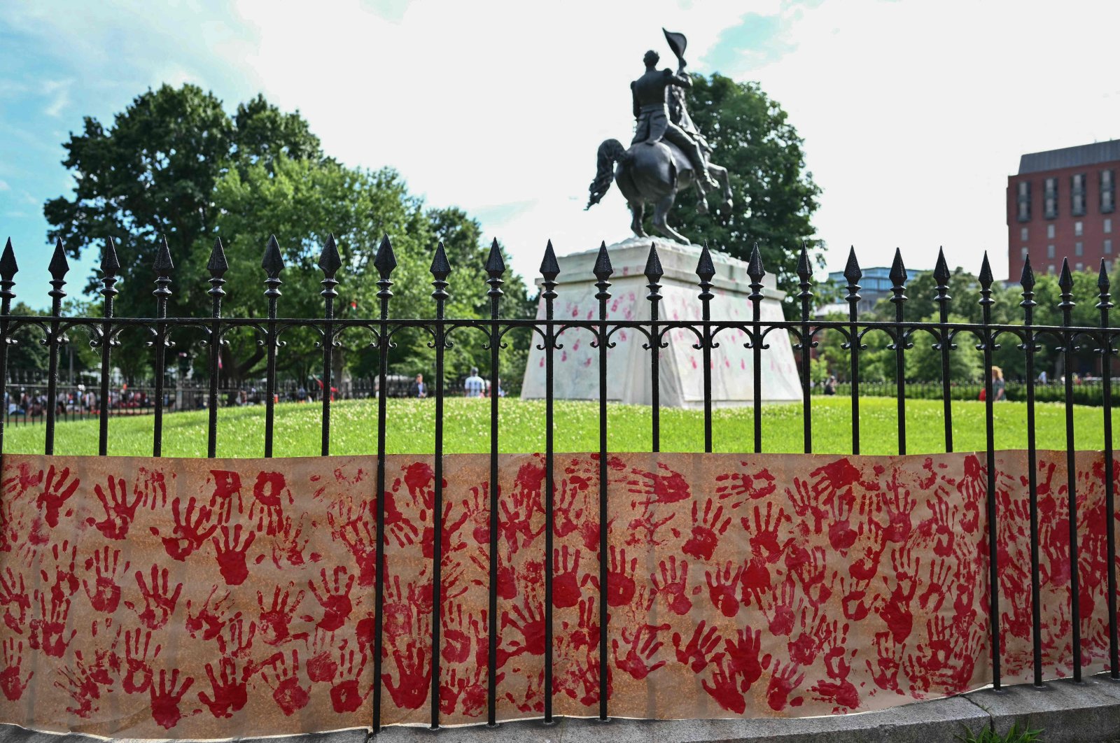 A banner with red handprints, left by pro-Palestinian demonstrators, sits as the base of a statue of Andrew Jackson in Lafayette Squre near the White House during a protest against Israel&#039;s actions in Gaza, in Washington, DC, US, June 8, 2024. (AFP Photo)