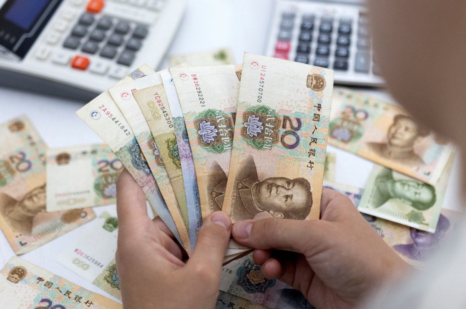 A woman holds Chinese yuan banknotes in this illustration taken May 30, 2022. (Reuters Photo)