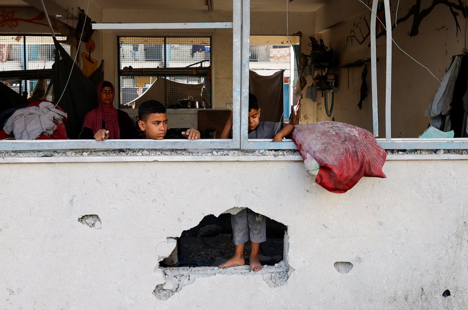 Palestinian boys stand near the damaged windows of a classroom in a UNRWA school, after the air strike on a neighboring house to the school in Khan Younis, in the southern Gaza Strip, June 21, 2024. (Reuters Photo)