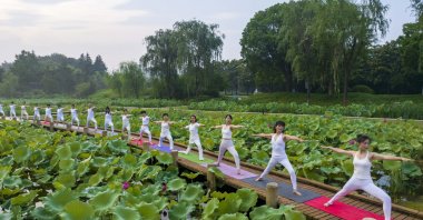 Yoga lovers practice yoga on the lotus Pond trestle at Tiande Lake Park in Taizhou, Jiangsu province, China, June 21, 2023. (Getty Images Photo)