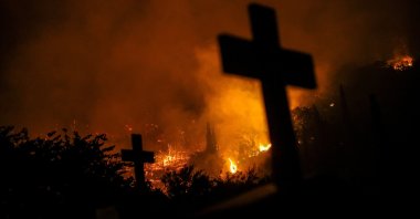 Crosses from graves are silhouetted as a wildfire burns in the village of Latas, Greece, June 22, 2024. (Reuters Photo)