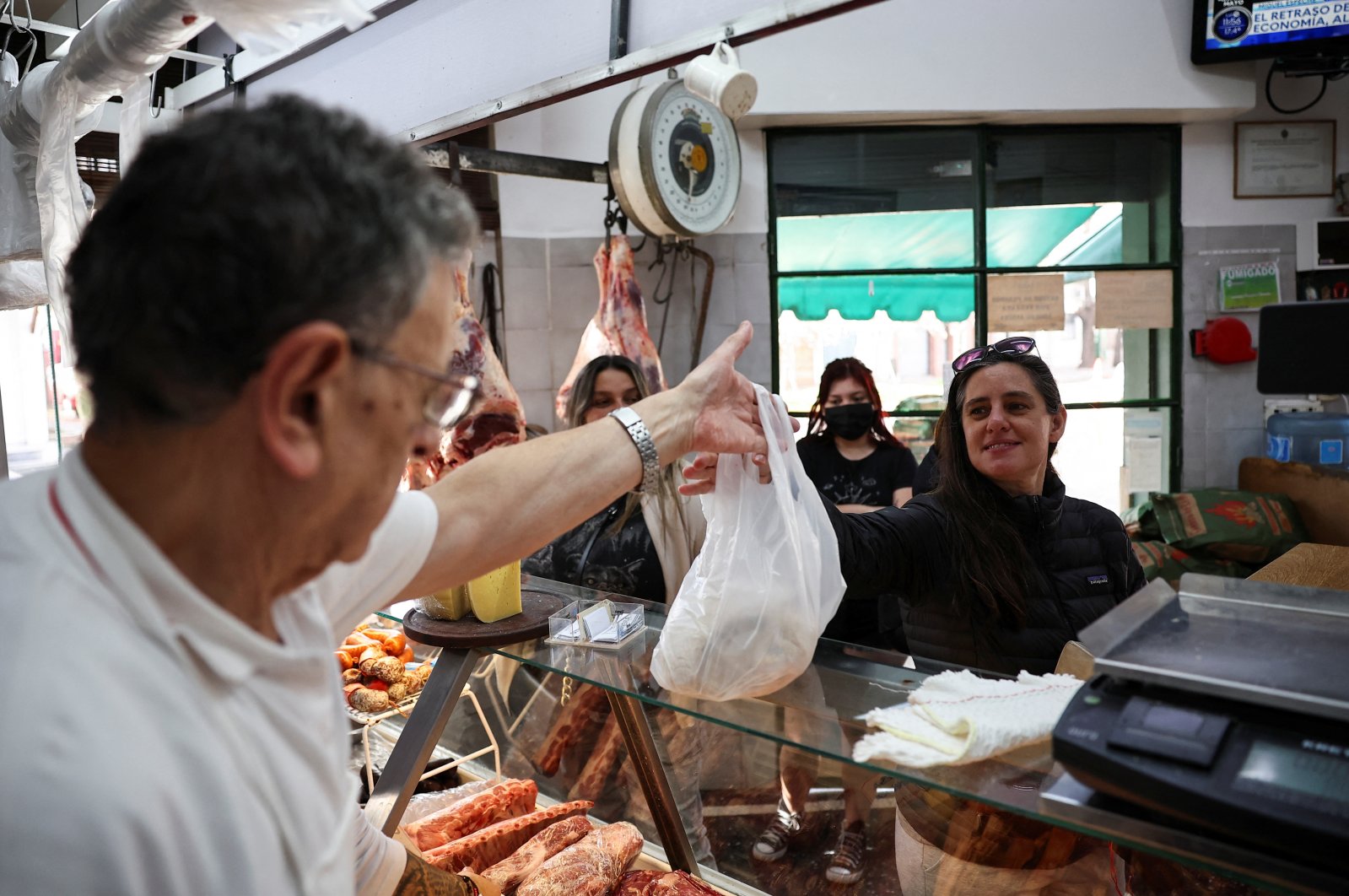 Butcher Dario Barrandeguy gives an order of meat in a bag to a customer at his shop, Buenos Aires, Argentina, June 10, 2024. (Reuters Photo)