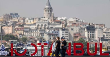 People walk past an Istanbul sign as Galata Tower is seen in the background in Istanbul, Türkiye, June 13, 2024. (AFP Photo)