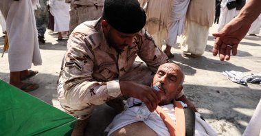 A man affected by the scorching heat is helped by a member of the Saudi security forces in Mina, near the holy city of Mecca, Saudi Arabia, June 16, 2024. (AFP Photo)