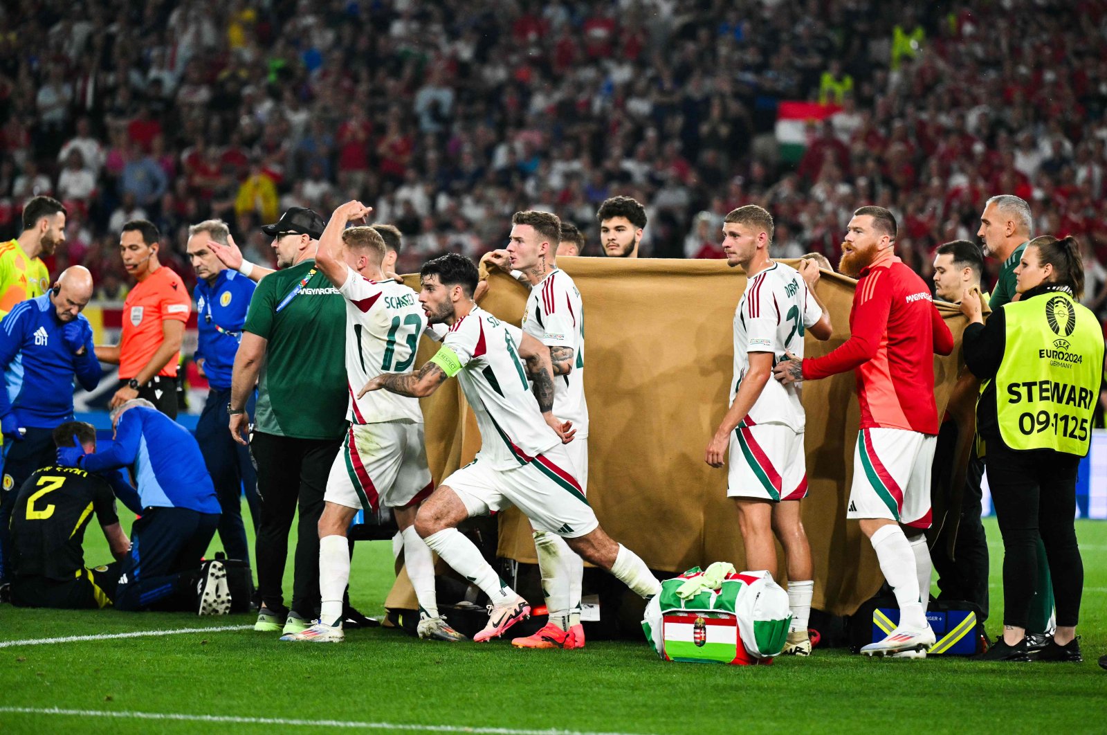 Players and stewards hold a cloth as Hungary&#039;s forward Barnabas Varga receives medical treatment after a collision during the UEFA Euro 2024 Group A football match between Scotland and Hungary, Stuttgart Arena, Stuttgart, Germany, June 23, 2024. (AFP Photo)