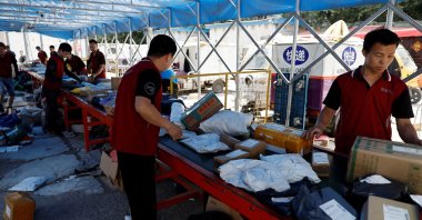 Delivery workers sort packages on a conveyor belt ahead of the "618" shopping festival at a logistics station in Beijing, China, June 12, 2023. (Reuters Photo)