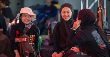 This picture shows members of the Indonesian metal band Voice of Baceprot (VOB), vocalist and guitarist Firda Kurnia (L), bassist Widi Rahmawati (C) and drummer Euis Siti Aisah (R) chatting before their concert in Jakarta, Indonesia, June 22, 2024. (AFP Photo)