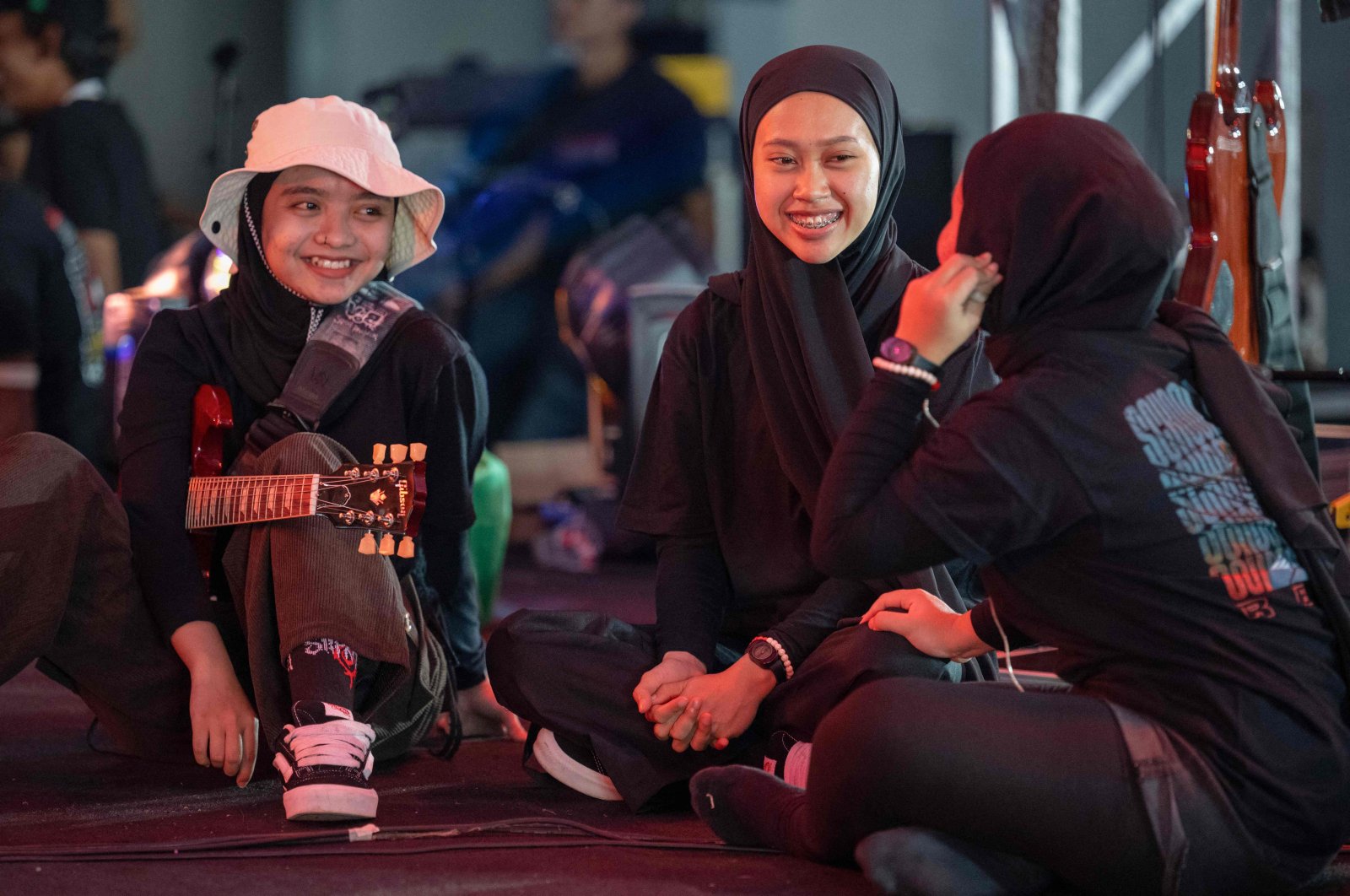 This picture shows members of the Indonesian metal band Voice of Baceprot (VOB), vocalist and guitarist Firda Kurnia (L), bassist Widi Rahmawati (C) and drummer Euis Siti Aisah (R) chatting before their concert in Jakarta, Indonesia, June 22, 2024. (AFP Photo)