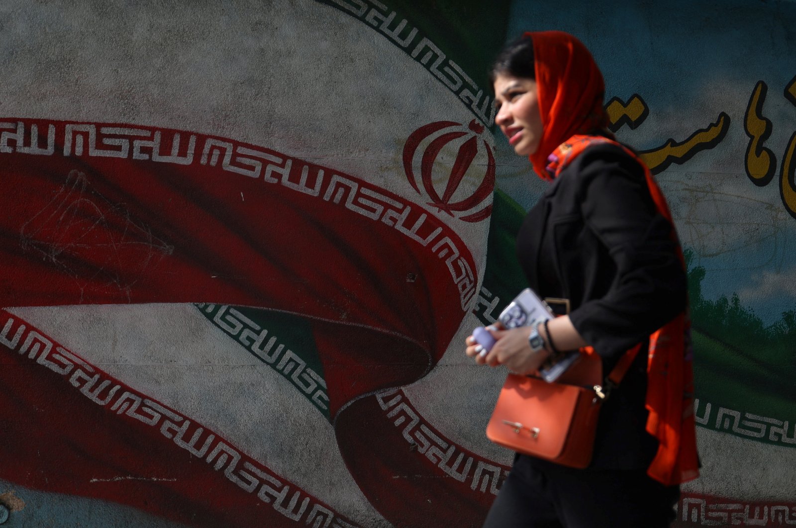 An Iranian woman passes in front of a mural with the Iranian flag on a street in Tehran, Iran, June 29, 2024. (Reuters Photo)