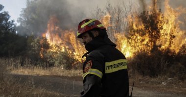 A firefighter stands by a fire while operating during a wildfire in the residential area of Stamata near Athens, Greece, June 30, 2024. (EPA Photo)