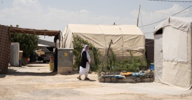 A Yazidi woman walks outside her tent at the Sharia refugee camp in northern Duhok province, Iraq, June 26, 2024. (AA Photo)