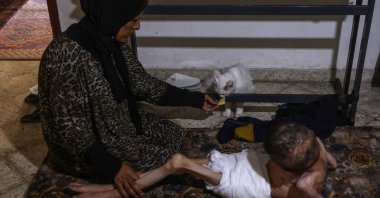 Palestinian man Bahaa al-Nimr, 19, who suffers from cerebral palsy and malnutrition, and his mother Sahar share a piece of bread with their cat at home in the Sheikh Radwan neighborhood in the north of Gaza City, Palestine, July 2, 2024. (AFP Photo)