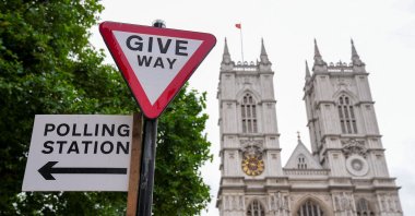 A polling station direction sign is attached to a street sign near Westminster Abbey, ahead of general elections, London, U.K., July 3, 2024. (Reuters Photo)