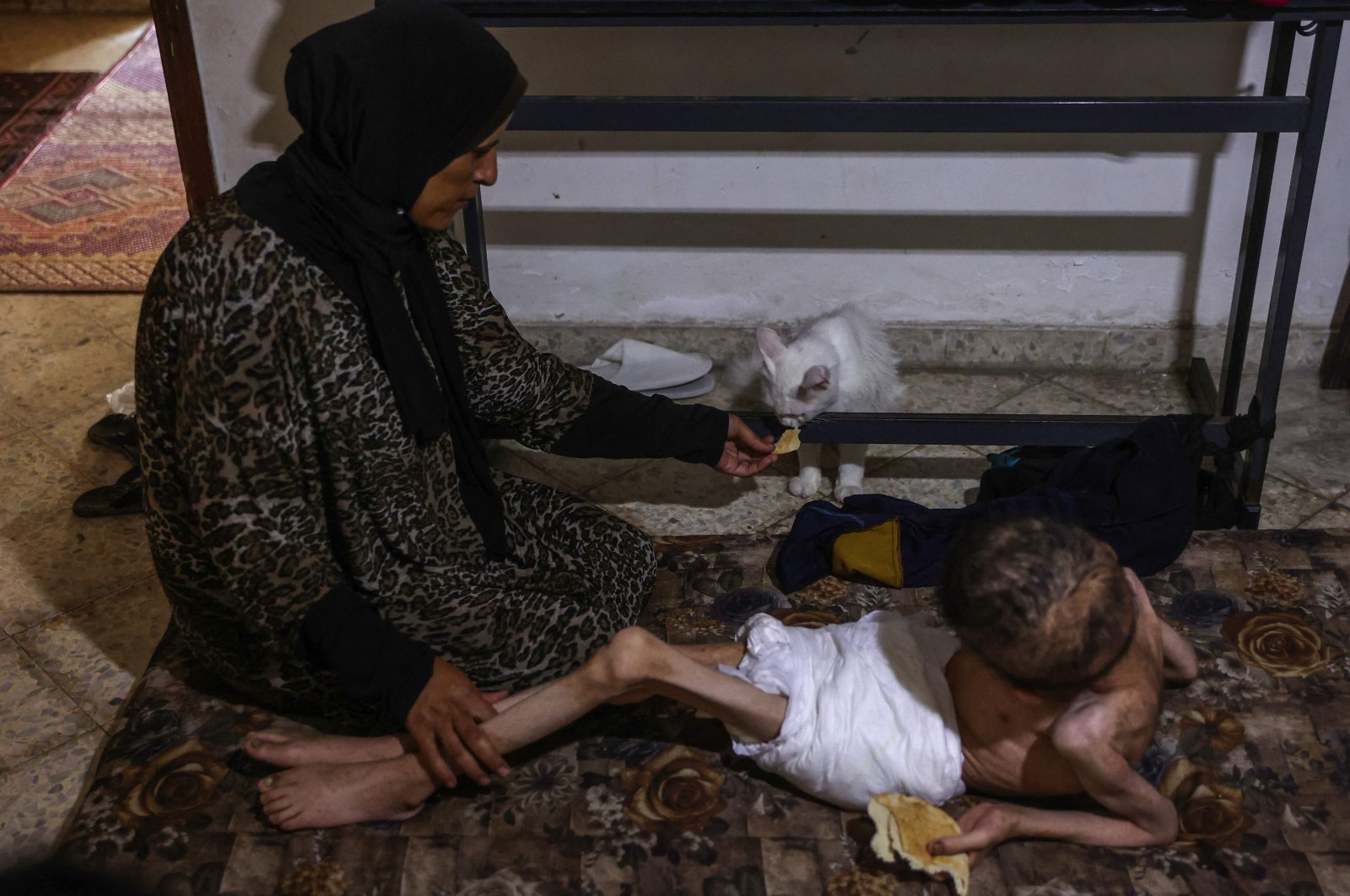 Palestinian man Bahaa al-Nimr, 19, who suffers from cerebral palsy and malnutrition, and his mother Sahar share a piece of bread with their cat at home in the Sheikh Radwan neighborhood in the north of Gaza City, Palestine, July 2, 2024. (AFP Photo)