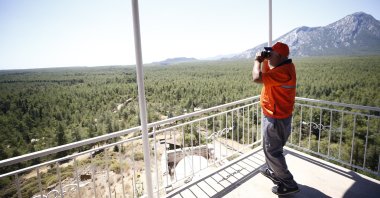 A personnel uses a binocular to watch over the forests in an observation tower, Antalya, western Türkiye, July 3, 2024. (AA Photo)