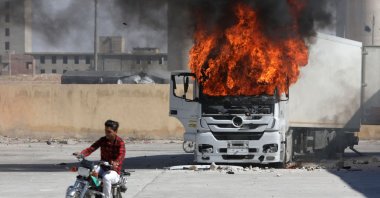 A man rides a motorcycle near a burning Turkish truck during anti-Turkish riots, al-Bab, Syria, July 1, 2024. (AFP Photo)