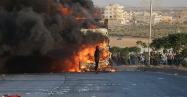 A protester stands in front a burning Turkish truck during protests against Türkiye in a Syrian opposition-held area north of Aleppo, Syria, July 1, 2024. (AFP Photo)