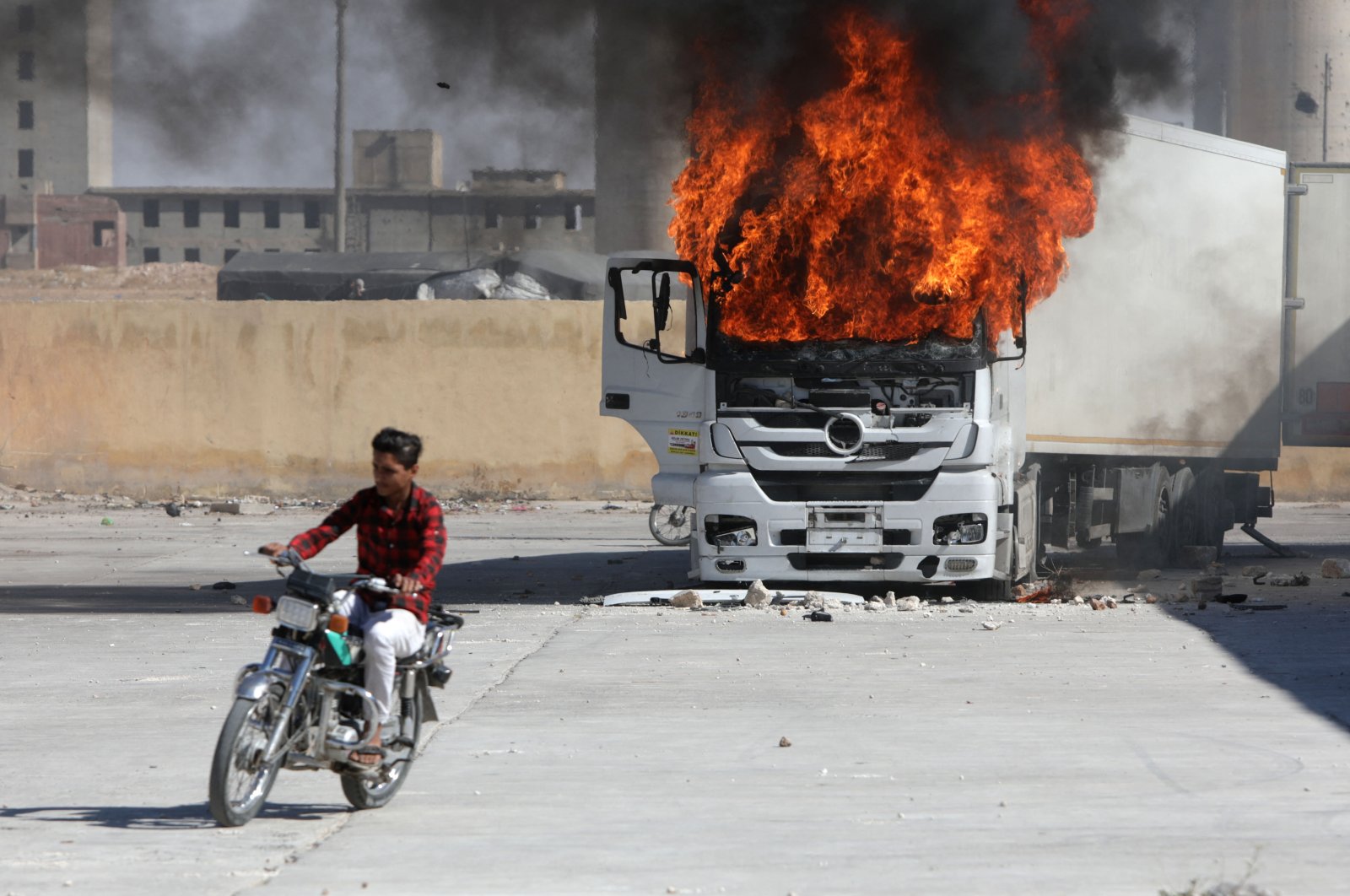 A man rides a motorcycle near a burning Turkish truck during anti-Turkish riots, al-Bab, Syria, July 1, 2024. (AFP Photo)