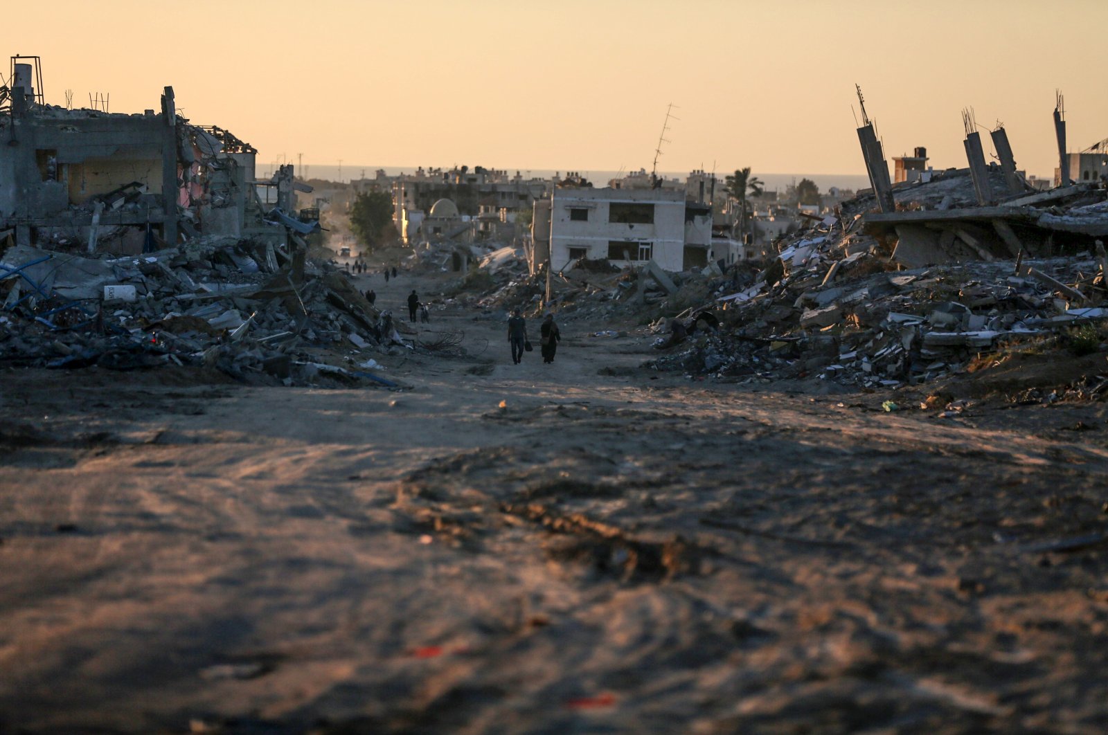 Palestinians are walking between damaged buildings in Khan Younis in the southern Gaza Strip on May 7, 2024. (Reuters File Photo)