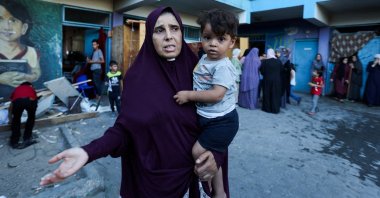 A Palestinian woman carrying a child reacts, after an Israeli airstrike on a U.N. school sheltering displaced people, in Nusairat, central Gaza Strip, Palestine, July 6, 2024. (Reuters Photo)