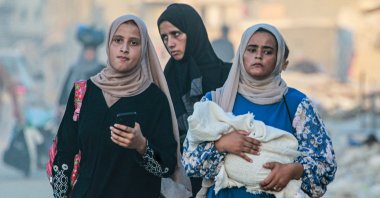 A woman holds a baby wrapped in a blanket as displaced Palestinians leave an area in east Khan Younis, Palestine, July 1, 2024. (AFP Photo)