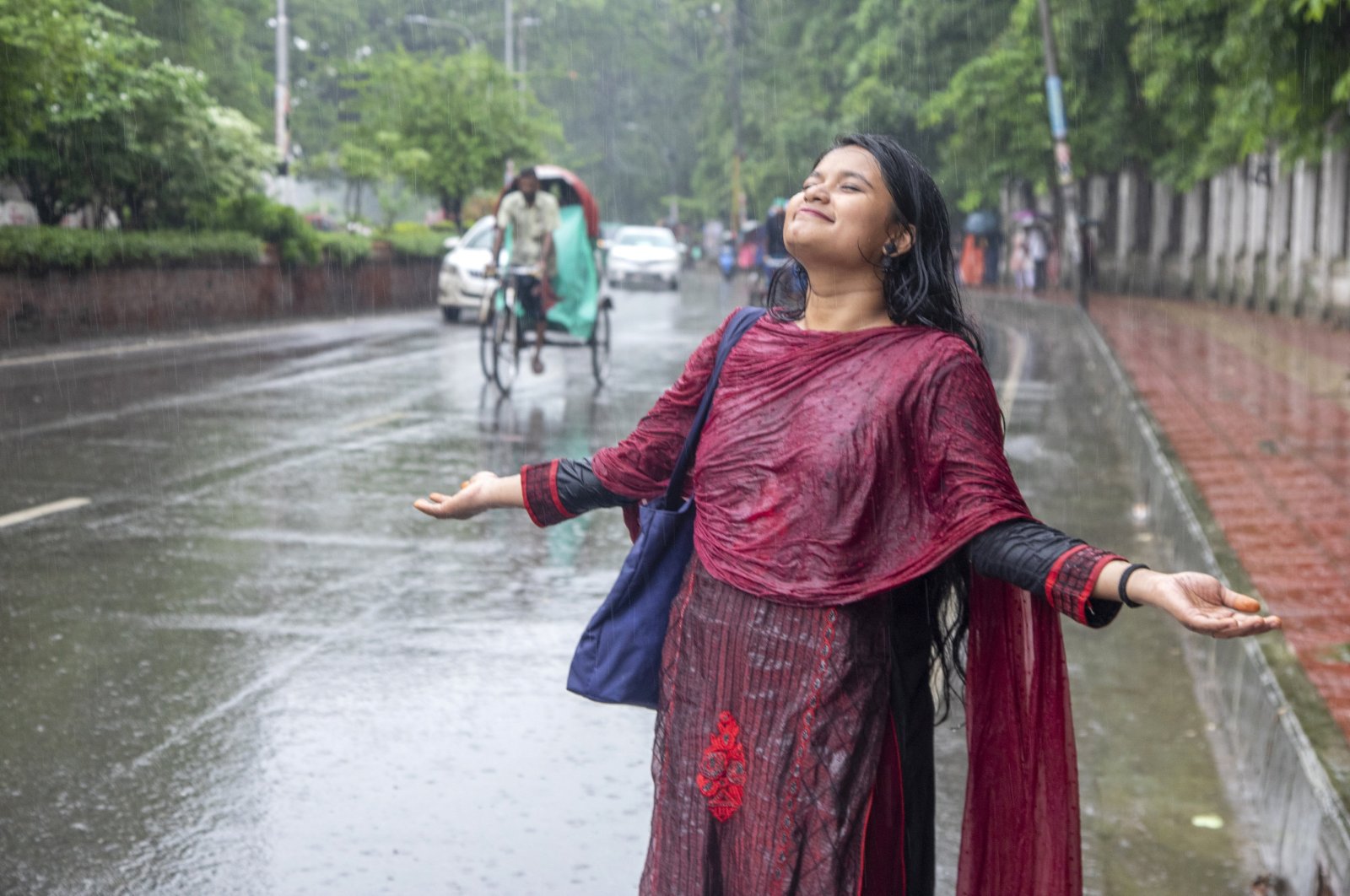 A university student enjoys the rain during a rainy day at the Dhaka University campus, Dhaka, Bangladesh, July 3, 2024. (EPA Photo)
