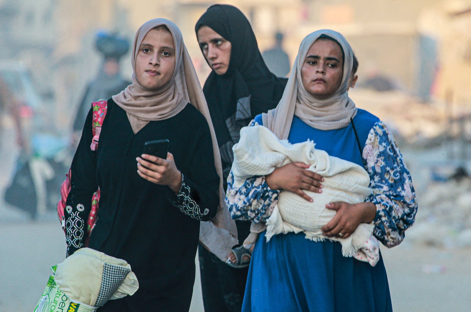A woman holds a baby wrapped in a blanket as displaced Palestinians leave an area in east Khan Younis, Palestine, July 1, 2024. (AFP Photo)