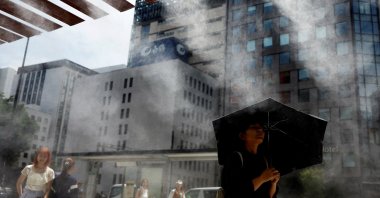 Passersby take a break under a cooling mist as the Japanese government issued a heatstroke alert in Tokyo and other prefectures, Tokyo, Japan, July 9, 2024. (Reuters Photo)