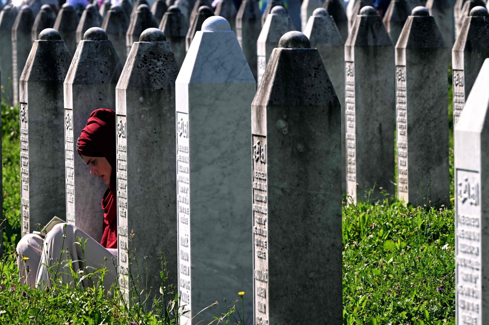A Bosnian Muslim woman sits among headstones as she prays next to graves of her relatives, Srebrenica, Bosnia-Herzegovina, July 11, 2024. (AFP Photo)