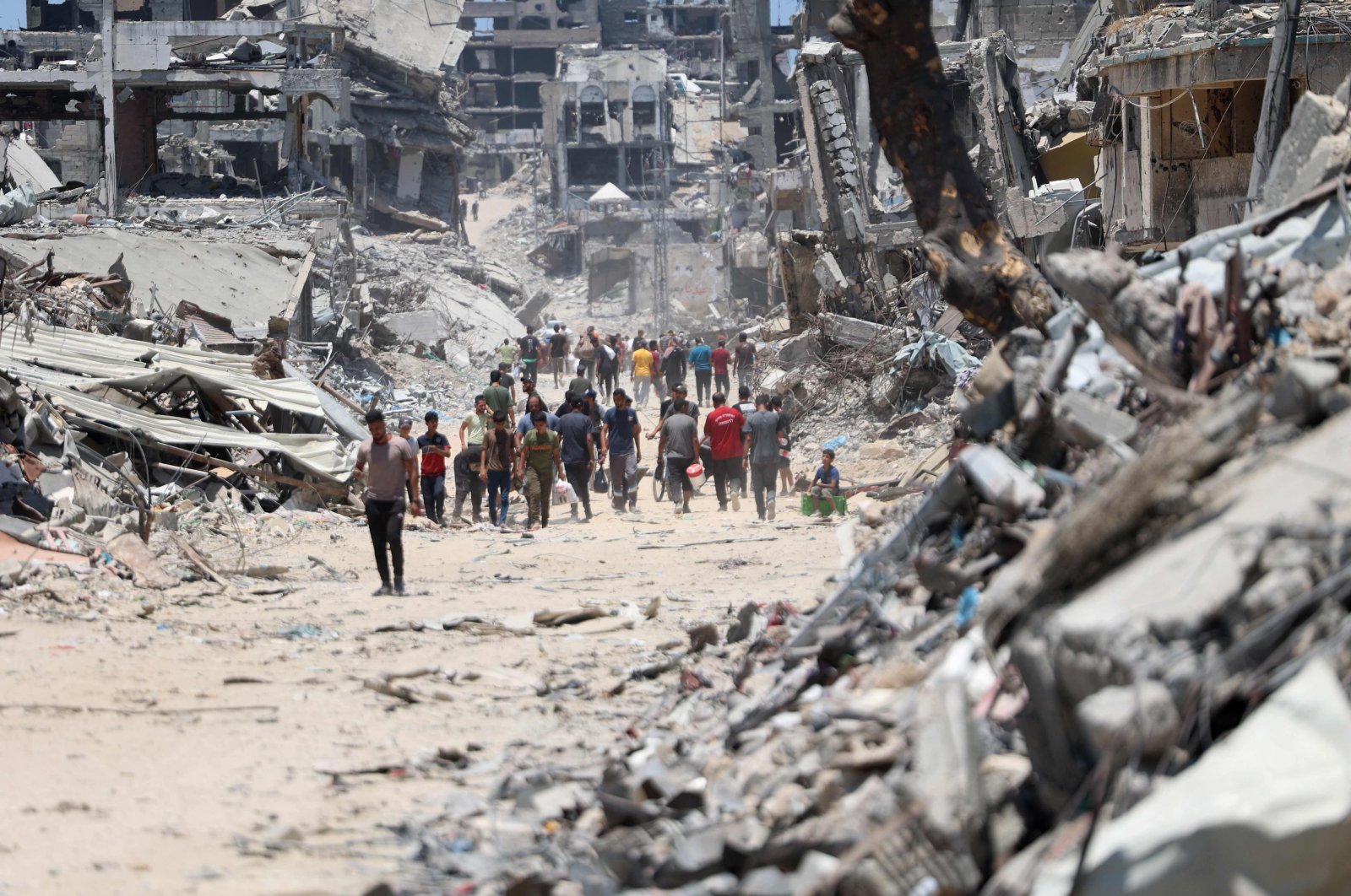 Palestinians make their way over the dirty rubble, past buildings destroyed by Israel after the Israeli military withdrew following two-weeks of attacks from the Shujaiya neighborhood, east of Gaza City, July 11, 2024. (AFP Photo)