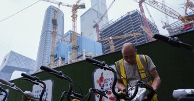 A worker puts on a cooling seat cover on a bicycle of bike-sharing service in Beijing's Central Business District, China, July 14, 2024. (Reuters Photo)