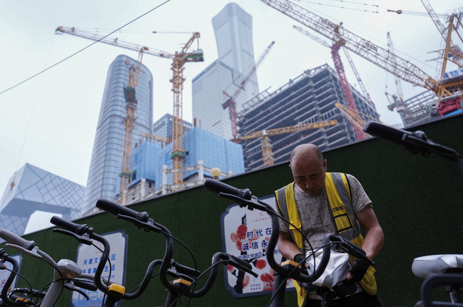 A worker puts on a cooling seat cover on a bicycle of bike-sharing service in Beijing&#039;s Central Business District, China, July 14, 2024. (Reuters Photo)