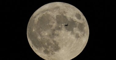 A plane passes in front of a full moon, Chicago, U.S., Aug. 30, 2023. (AP Photo)