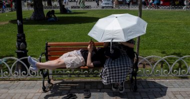 People shelter from the sun with an umbrella as they pause at Sultanahmet Square, one of the city's most well-known tourist attractions, Istanbul, Türkiye, June 28, 2024. (Reuters Photo)