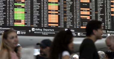 Passengers look at screens informing on the flight situation at the Zurich Airport in Kloten, Switzerland, July 19, 2024. (EPA Photo)