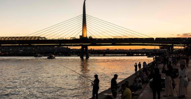 People sit and fish on the banks of the Golden Horn at sunset, Istanbul, Türkiye, June 17, 2024. (AFP Photo)