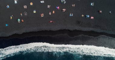 Sunbathers on a black sand beach photographed from directly above, Tenerife, Spain, Oct. 11, 2021. (Getty Images)