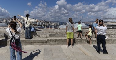 People take pictures at the courtyard of the Süleymaniye Mosque backdropped by the Bosporus, Istanbul, Türkiye, June 29, 2024. (EPA Photo)