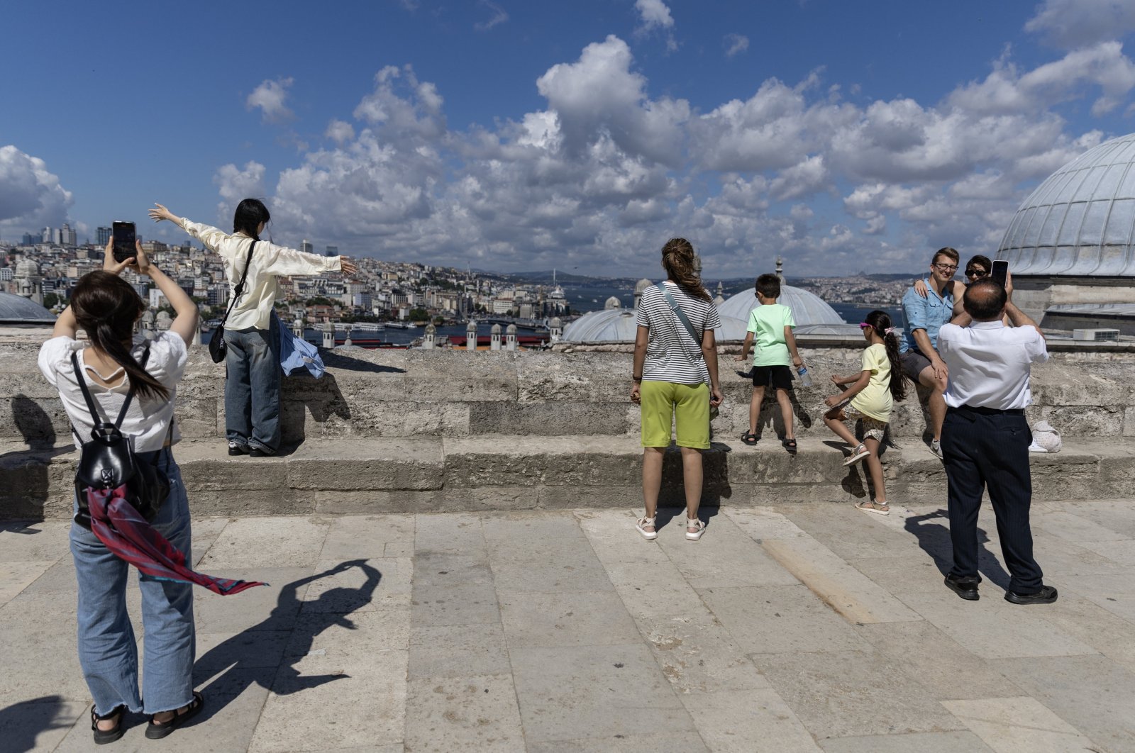 People take pictures at the courtyard of the Süleymaniye Mosque backdropped by the Bosporus, Istanbul, Türkiye, June 29, 2024. (EPA Photo)