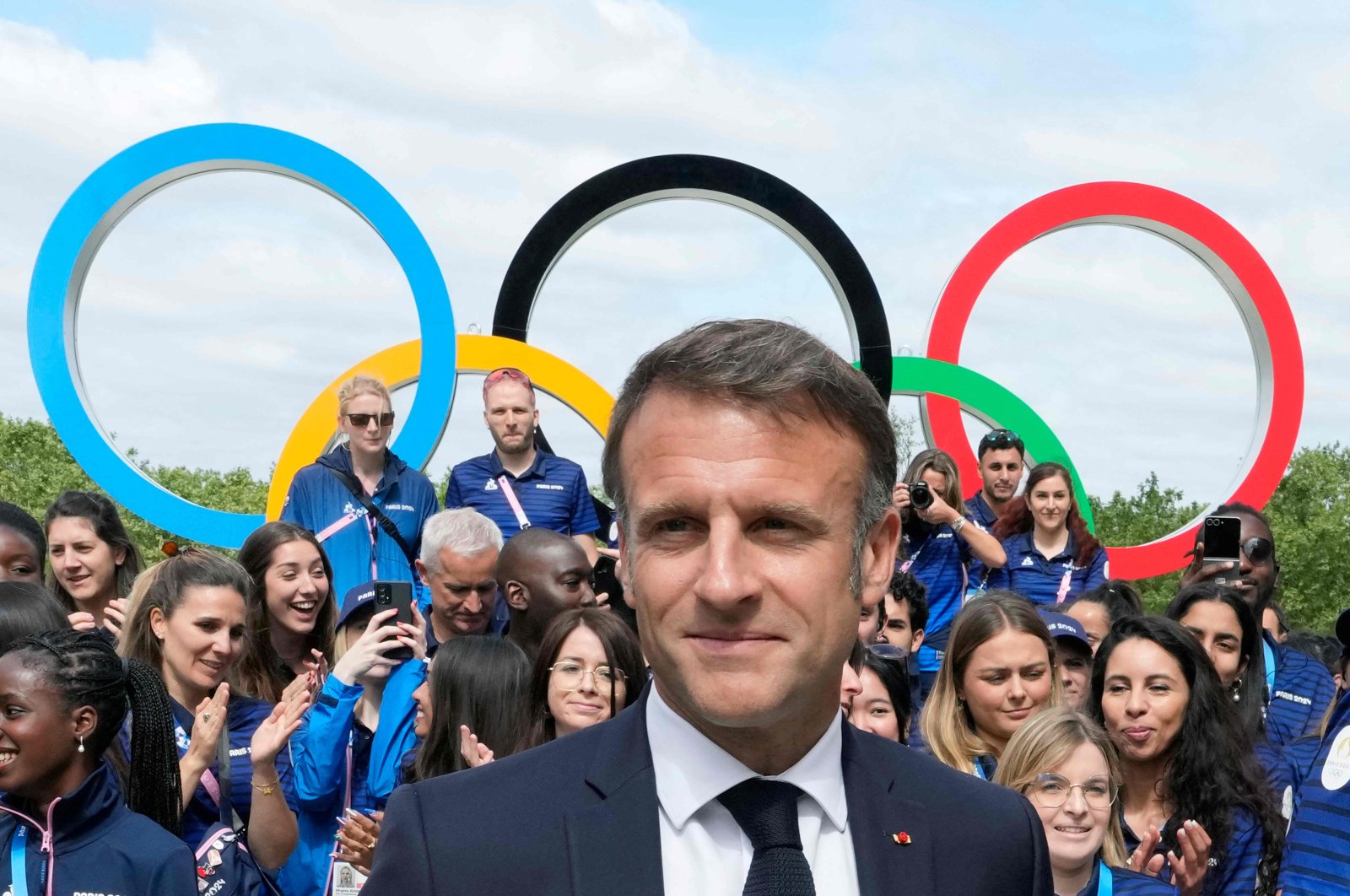 French President Emmanuel Macron looks on with the Olympic rings displayed behind him, leaves after posing with French athletes during a visit at the Olympic Village head of the opening ceremony of the Paris 2024 Olympic and Paralympic Games, in Saint-Denis, Paris, France, July 22, 2024. (AFP Photo)