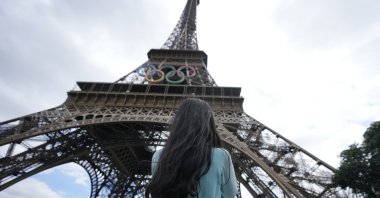 A tourist stands in front of the Eiffel Tower ahead of the 2024 Summer Olympics, Paris, France, July 22, 2024. (AP Photo)