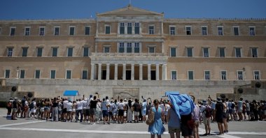 Tourists protect themselves from the sun while watching the presidential guards in front of the Greek parliament, as the country faces temperatures surpassing 40 degrees Celsius (104 degrees Fahrenheit), Athens, Greece, July 18, 2024. (Reuters Photo)