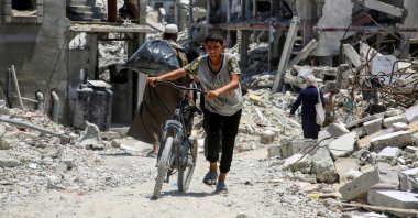A Palestinian pushes a bicycle as he walks past the rubble of houses destroyed during the Israeli attacks in Khan Younis in the southern Gaza Strip, July 10, 2024. (Reuters Photo)