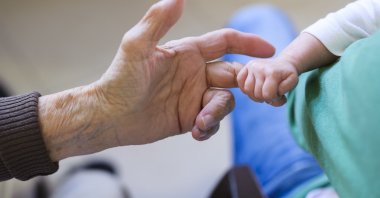 A baby holding the finger of her great-grandmother&#039;s hand, July 29, 2024. (Getty Images Photos)