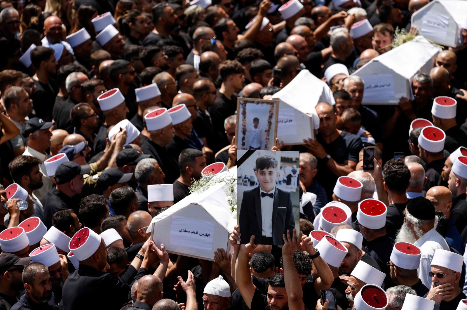 Mourners carry the coffins and pictures of people killed in a rocket in Majdal Shams, Israel-occupied Golan Heights, July 28, 2024. (AFP Photo)