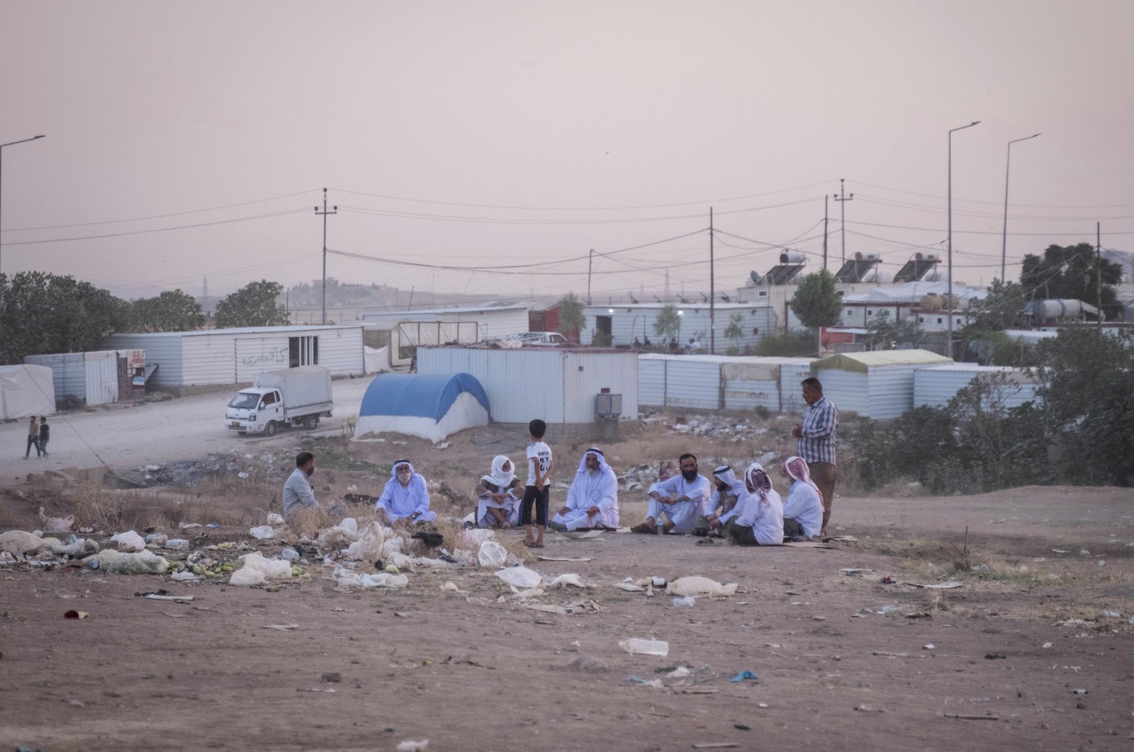 Yazidi men sit together during sunset in the Sharya displacement camp in Duhok, Iraq, June 21, 2024. (AP Photo) 