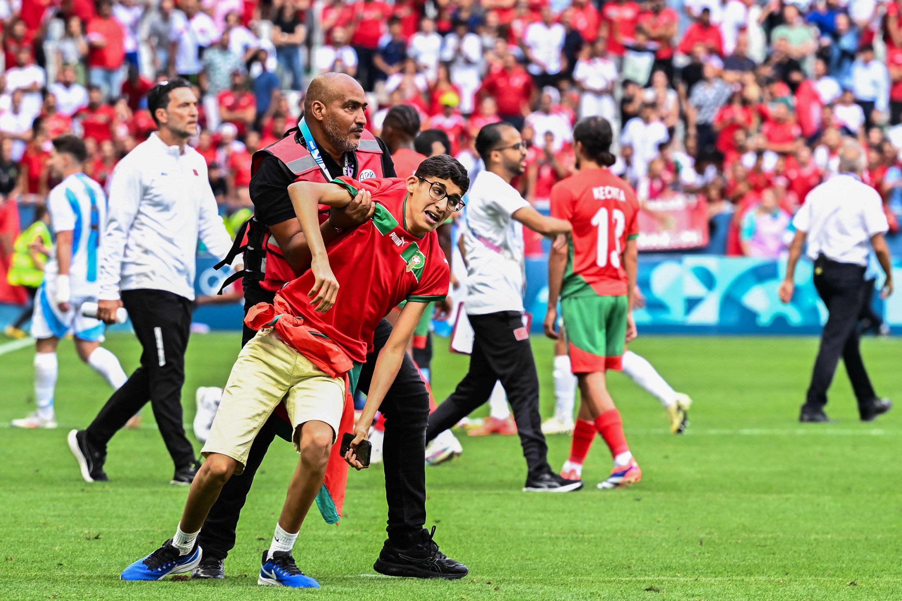 A member of security holds a fan of Morocco after numerous Morocco fans invaded the pitch at the end of the men's group B football match between Argentina and Morocco during the Paris 2024 Olympic Games at the Geoffroy-Guichard Stadium, Saint-Etienne, France, July 24, 2024. (AFP Photo)