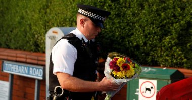 A police officer handles flowers, given by residents, to put them behind the police cordon near the scene of a stabbing incident in Southport, Britain, July 29, 2024. (Reuters Photo)