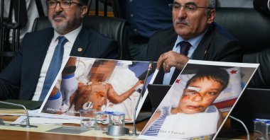 Two lawmakers of the ruling Justice and Development Party (AK Party) show pictures of children killed in stray dog attacks during parliamentary talks on the draft law, the capital Ankara, Türkiye, July 17, 2024. (AA Photo)