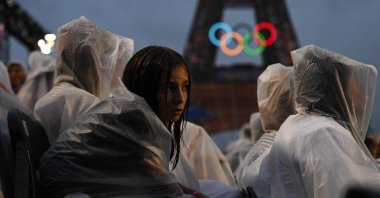Attendees wear rain covers as they sit in the stands during the opening ceremony of the Paris 2024 Olympic Games as the Eiffel Tower is seen in the background, Paris, France, July 26, 2024. (AFP Photo)